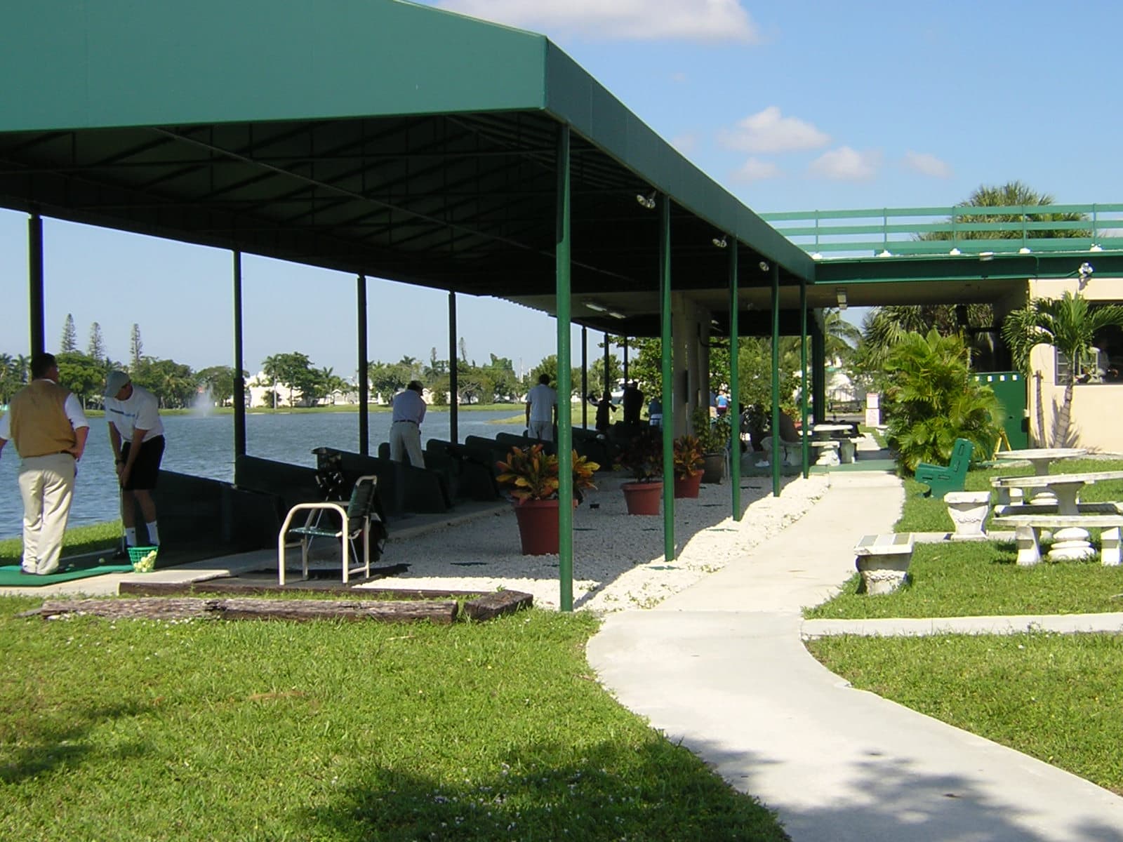 Golfers hitting balls toward the lake at Aqua Golf’s shaded driving range